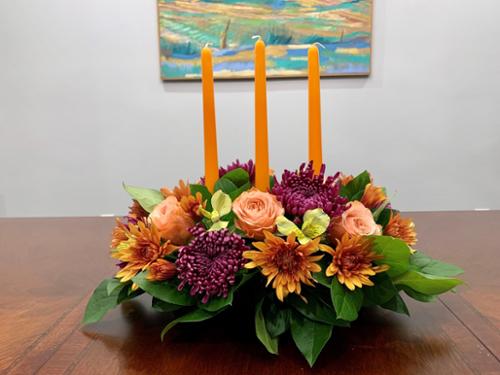 18" oval centerpiece with 3 taper candles. Made of a premium selection of flowers in autumnal palette. An elegant addition to the celebration.